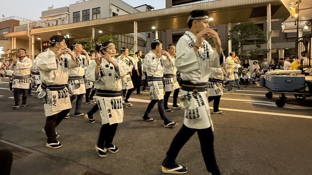 揃いの白い半纏で笛を吹くねぶた祭の囃子方